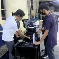 Two TINKIT technicians setting up equipment from a road case