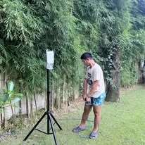 A TINKIT technician beside an access point on a tripod among bamboo