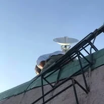 A TINKIT technician on a rooftop under an antenna mast