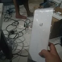 A hand holding an outdoor access point before mounting