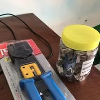 A crimping tool beside a jar of network connectors