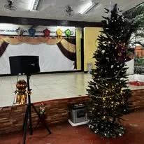 A speaker on a stand by the stage, a power station at the Christmas tree